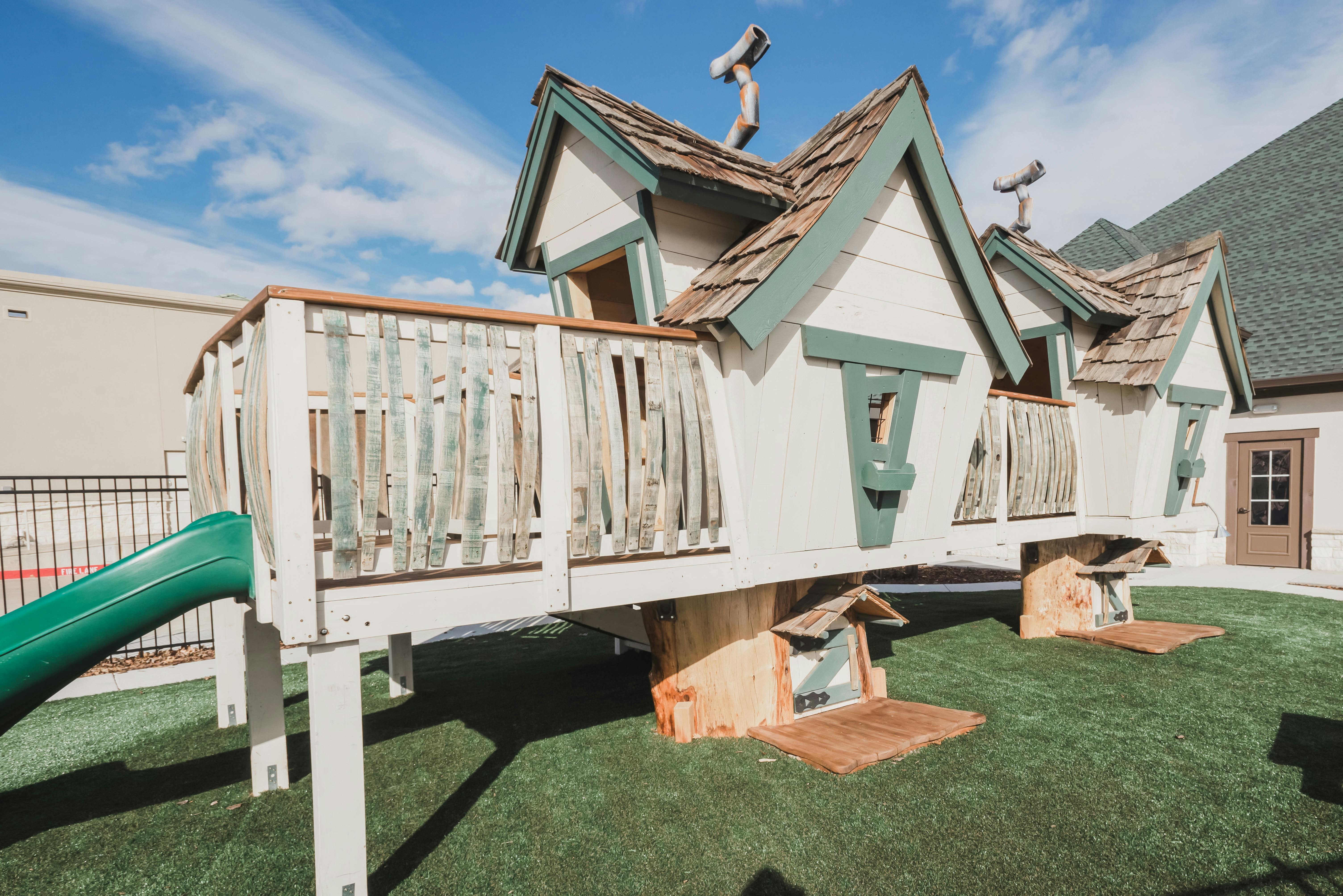 Playhouse with a green slide on artificial grass