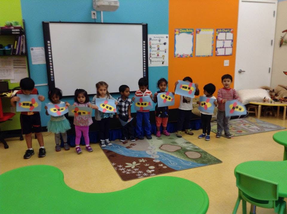 Group of children holding up artwork in a classroom