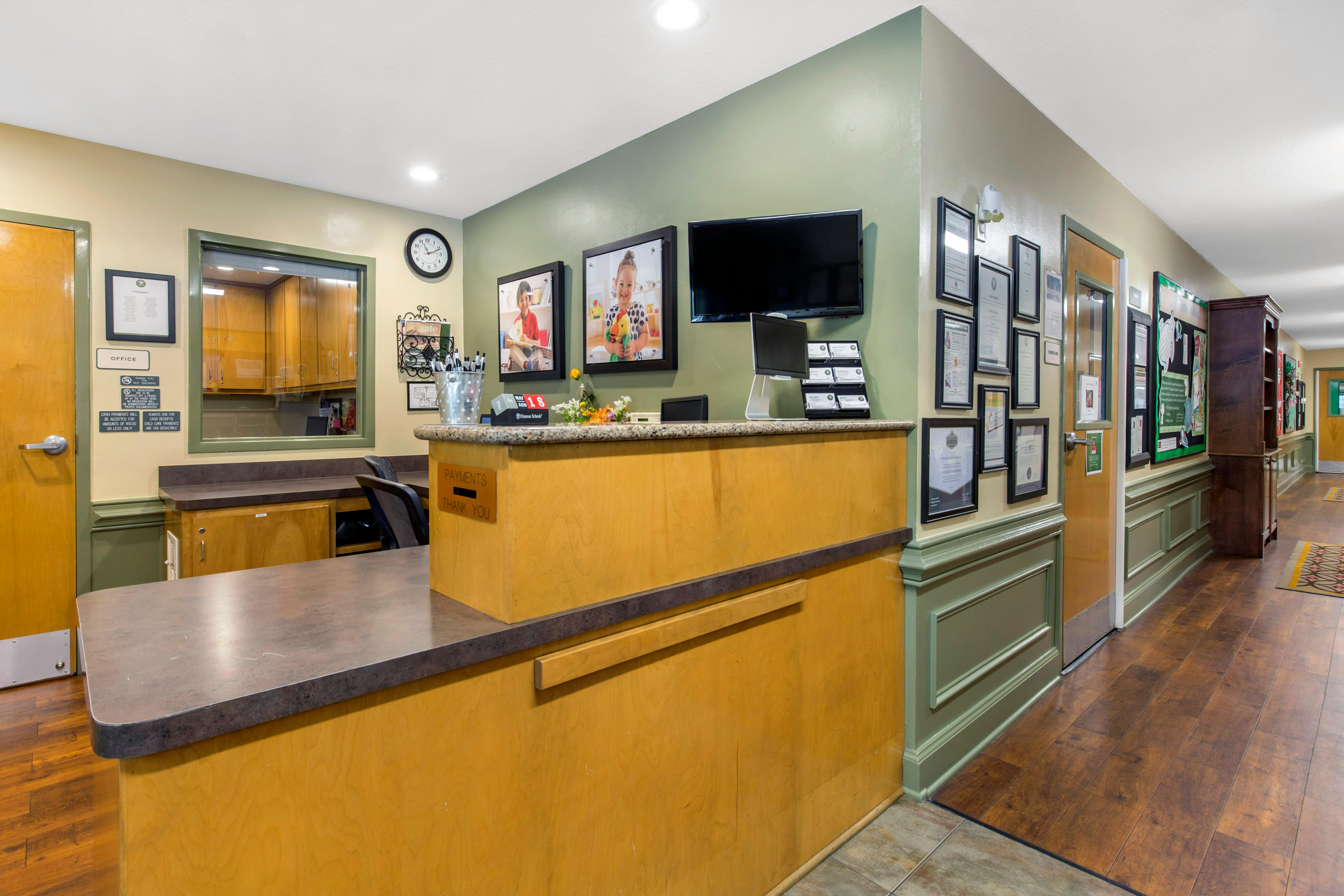 Reception desk with office window and a hallway of framed certificates