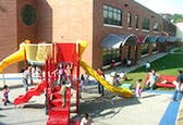 Children playing on a red and yellow playground slide structure