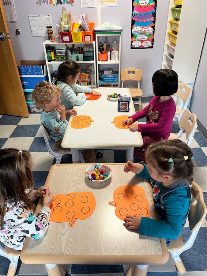 Children at tables doing crafts with orange paper cutouts