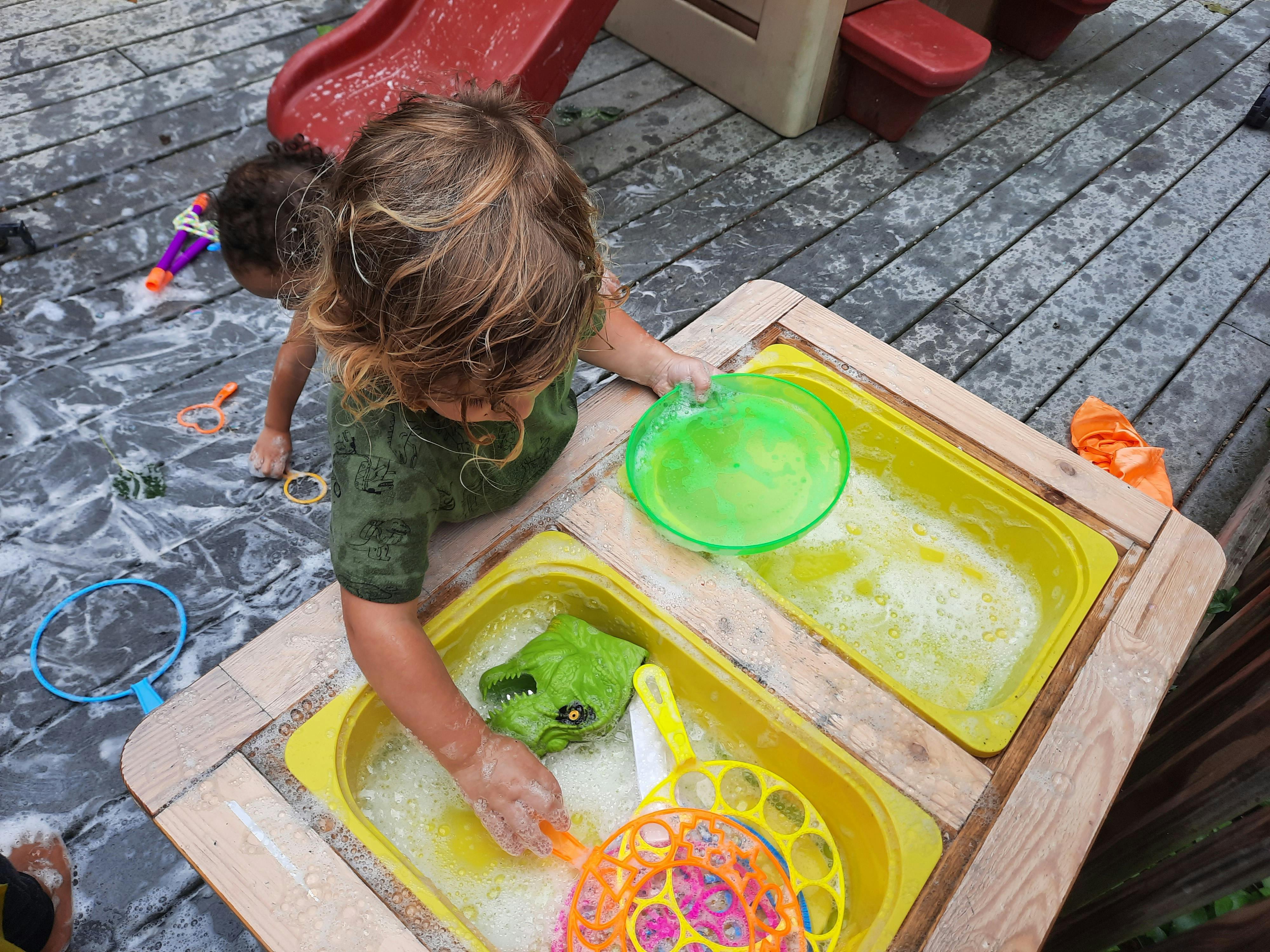 Children playing with toys in a soapy water table