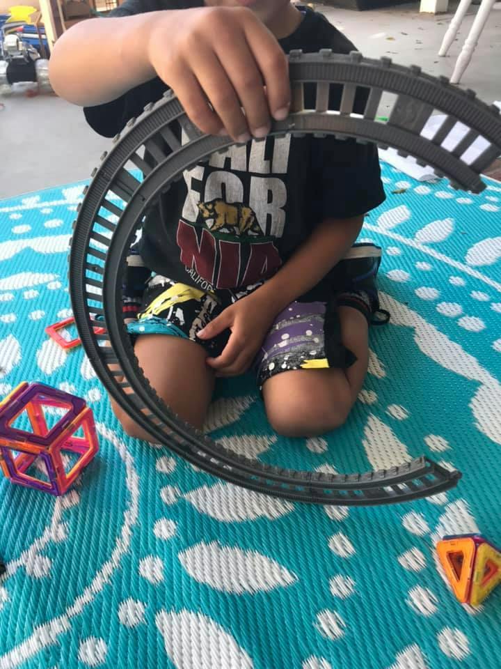 Child holding a curved toy train track piece