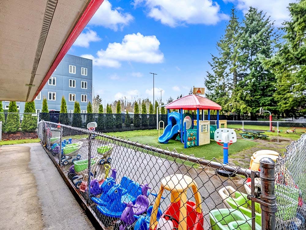 Playground with a slide, playhouse, and various ride-on toys