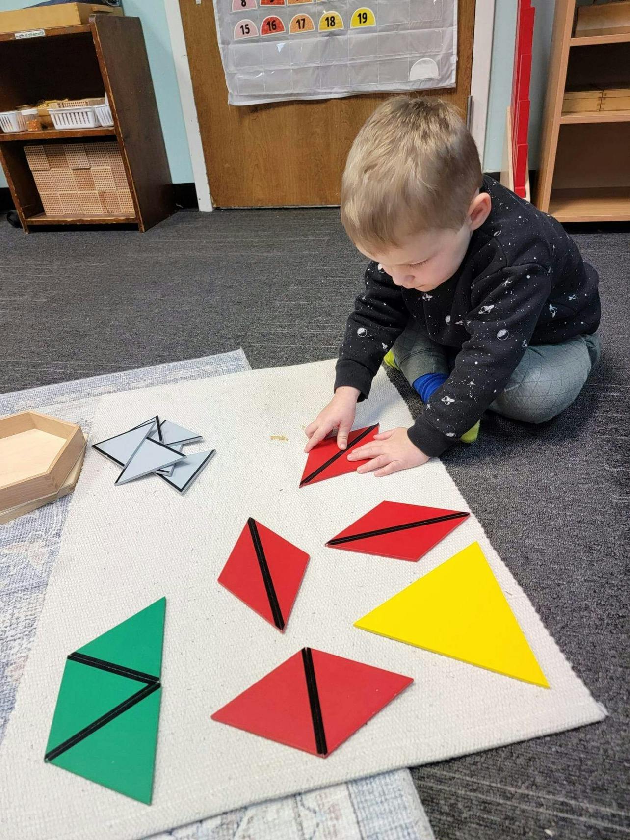 Child playing with colorful geometric shapes on a mat