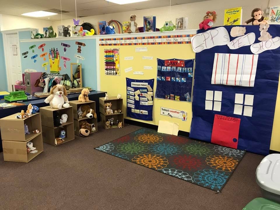 Classroom with stuffed animals on shelves and a large blue fabric house