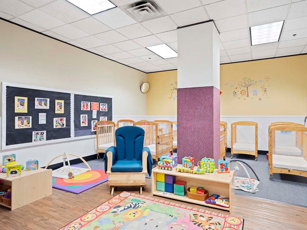 Baby room with several cribs, a blue rocking chair, and play mats