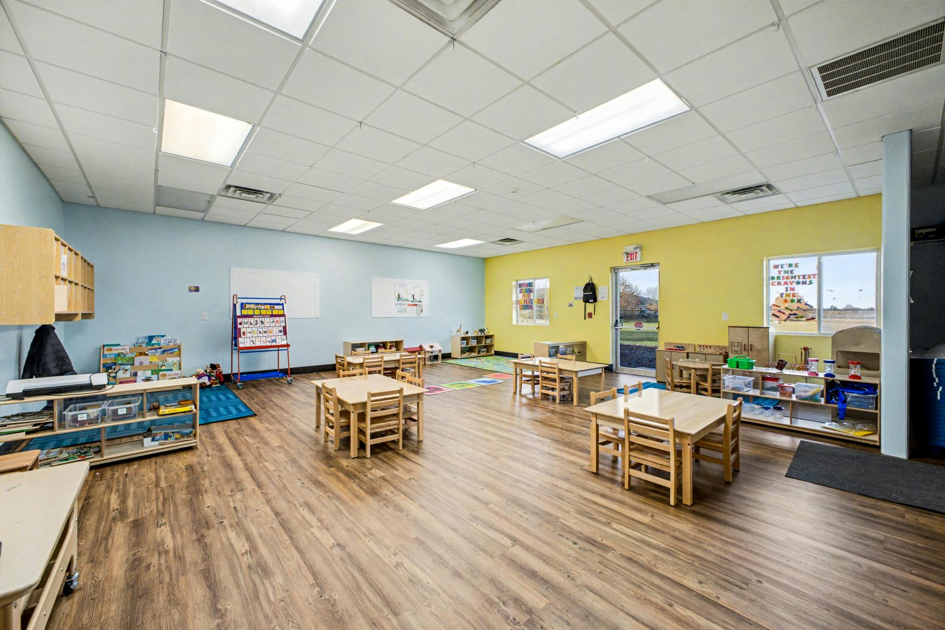 Empty classroom with small tables and chairs, toys, and supplies
