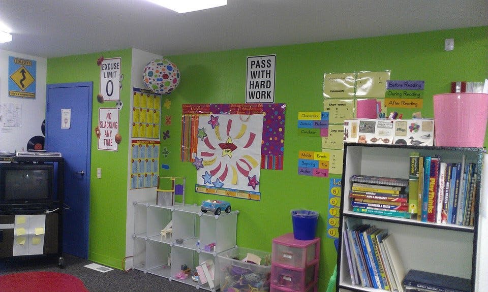 Classroom with green walls, shelves, and educational posters