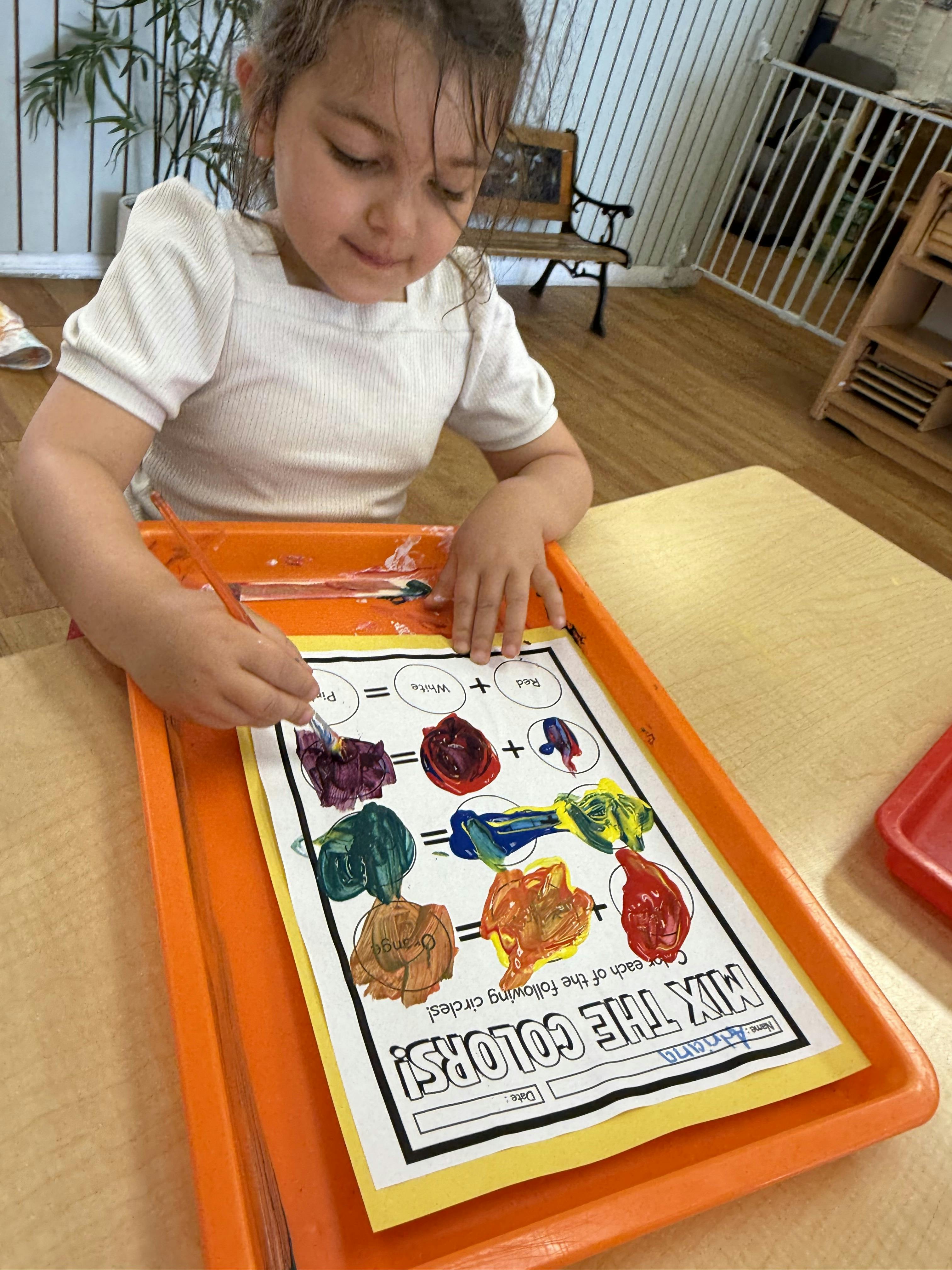 Child painting on a worksheet about mixing colors