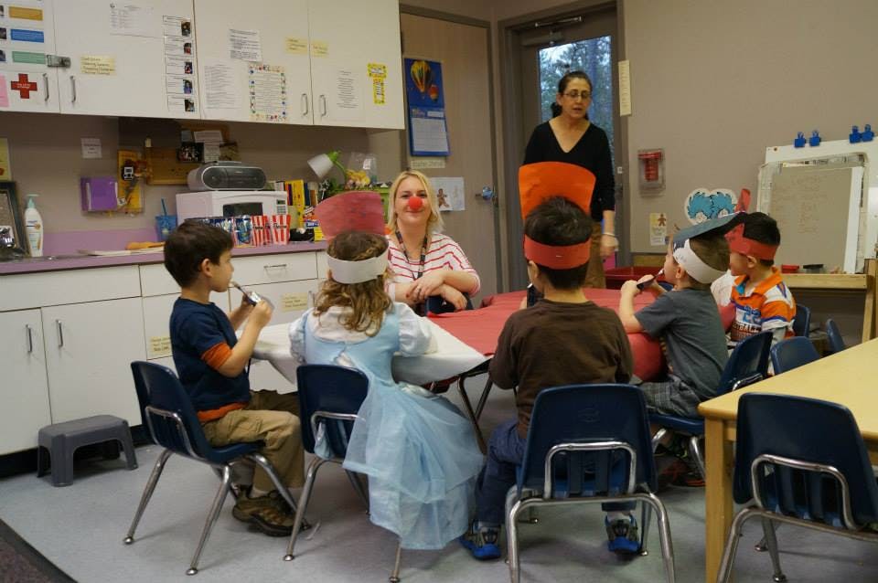 Adults and children gathered around a table in a classroom
