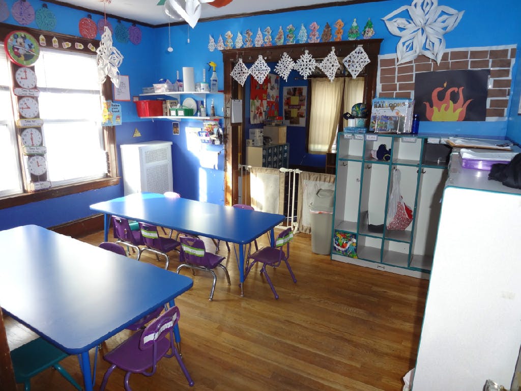 Classroom with blue walls, two blue tables, and purple chairs
