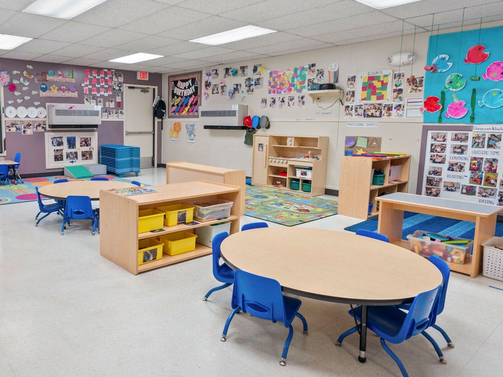 Classroom with small tables and chairs, shelves, and colorful decorations