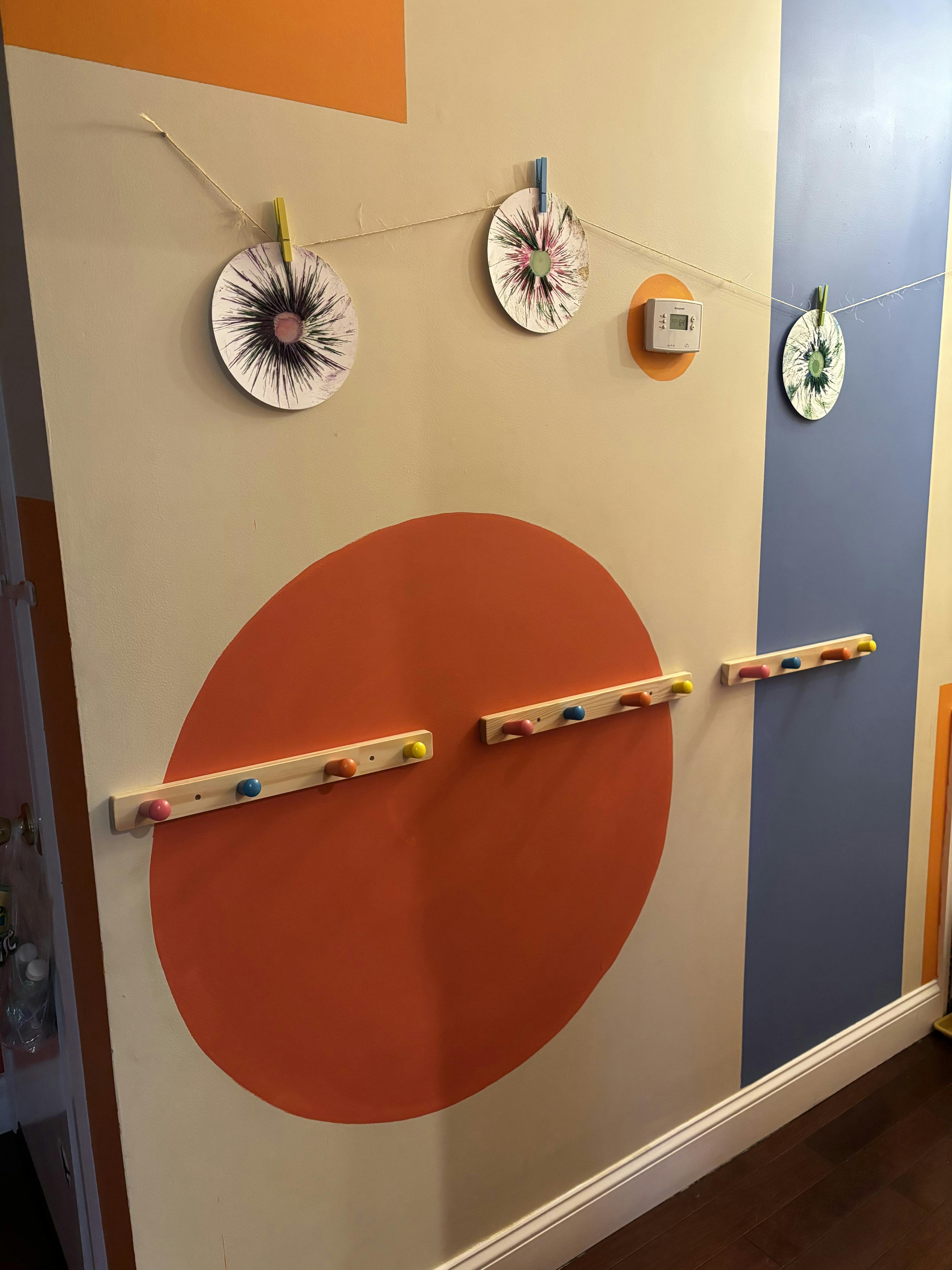 Wall with orange circle, blue stripe, and clothesline with paper cutouts
