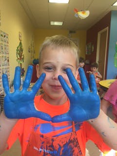 Child with blue paint on hands