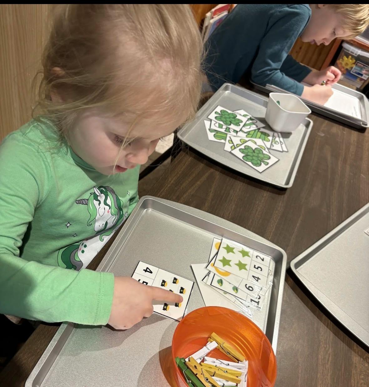 Child counting images on a learning card at a table