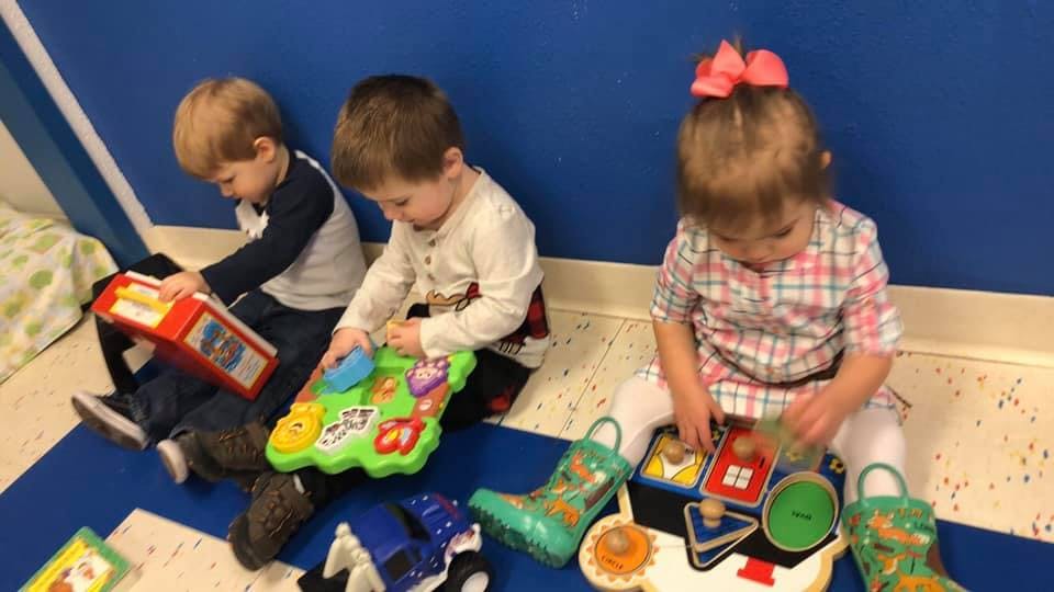 Three children playing with toys on the floor