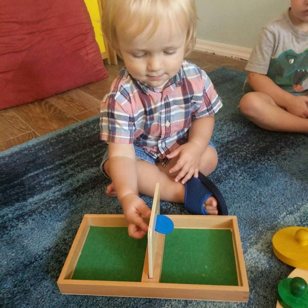 Child playing with a wooden puzzle on a blue rug