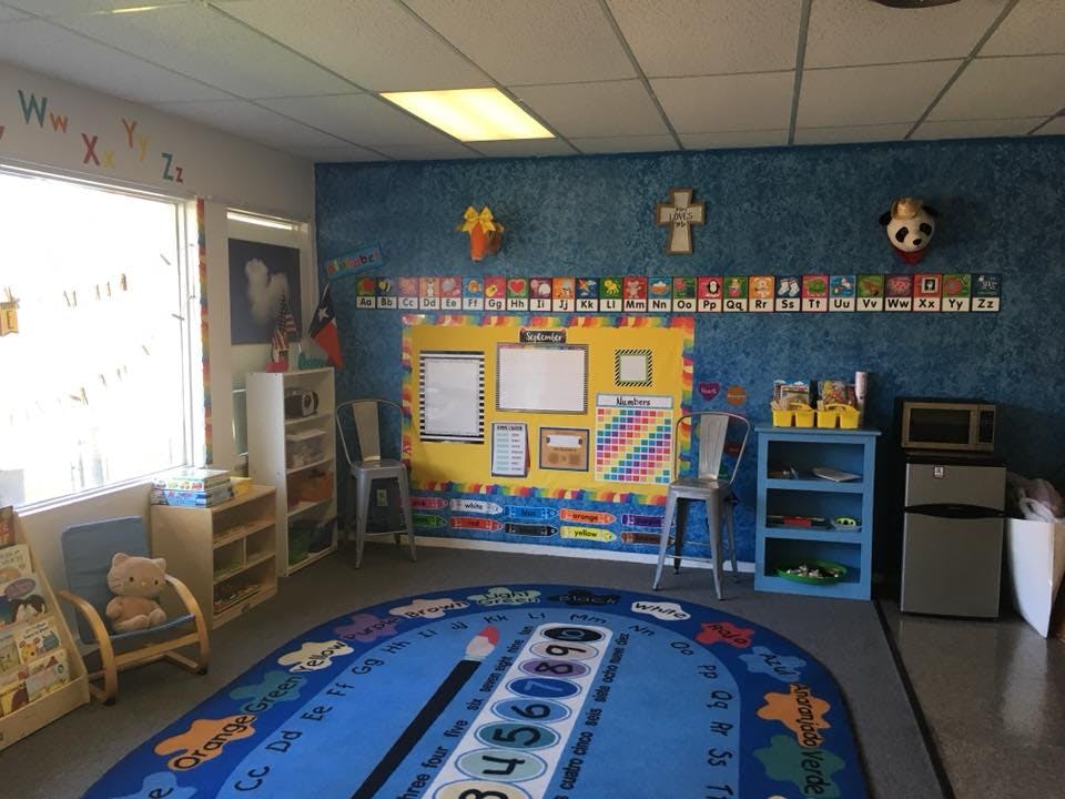 Classroom with a blue rug, bulletin board, and small chairs