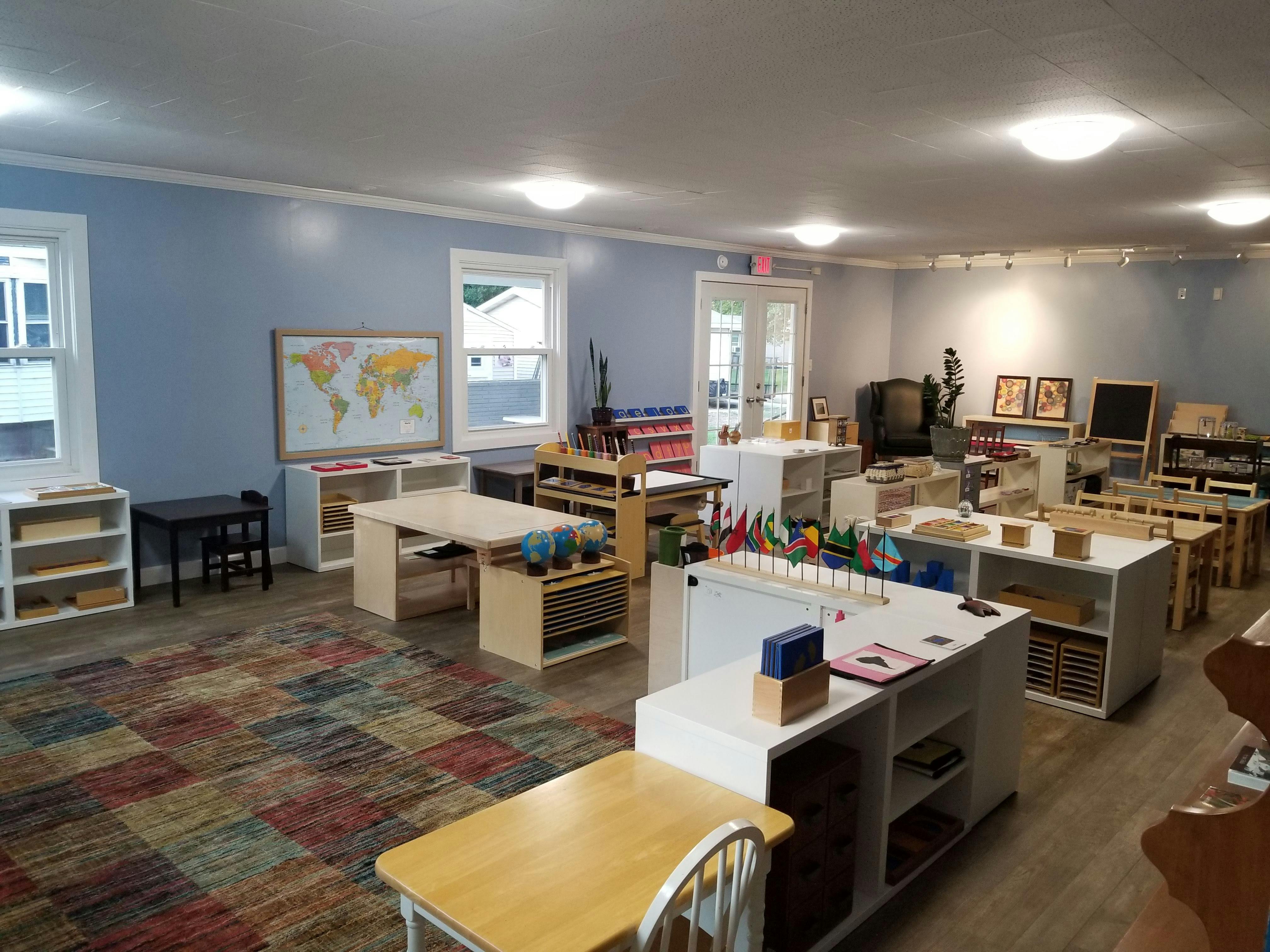 Classroom with tables, shelves, and a world map on the wall