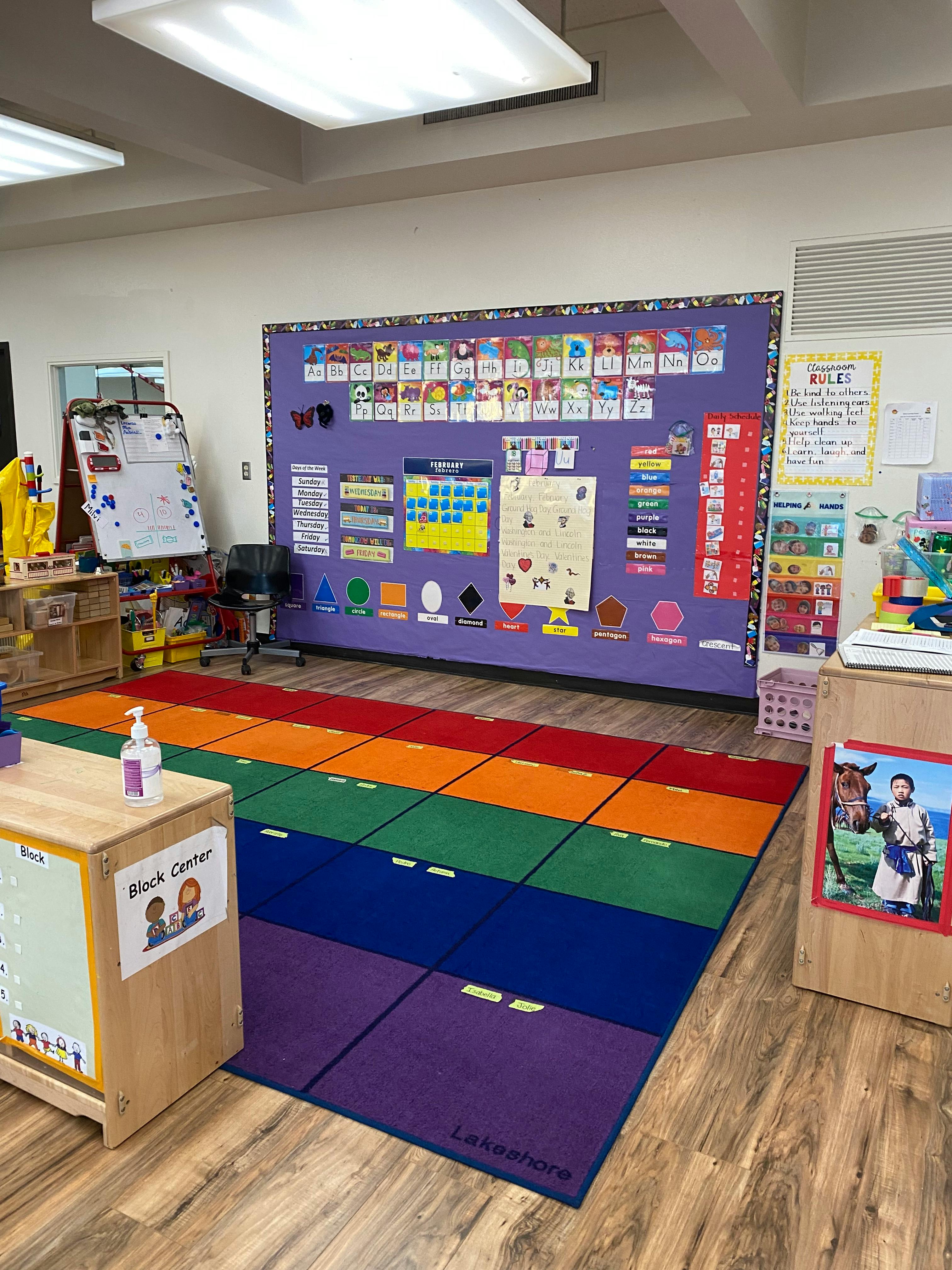Classroom with a rainbow rug and a bulletin board