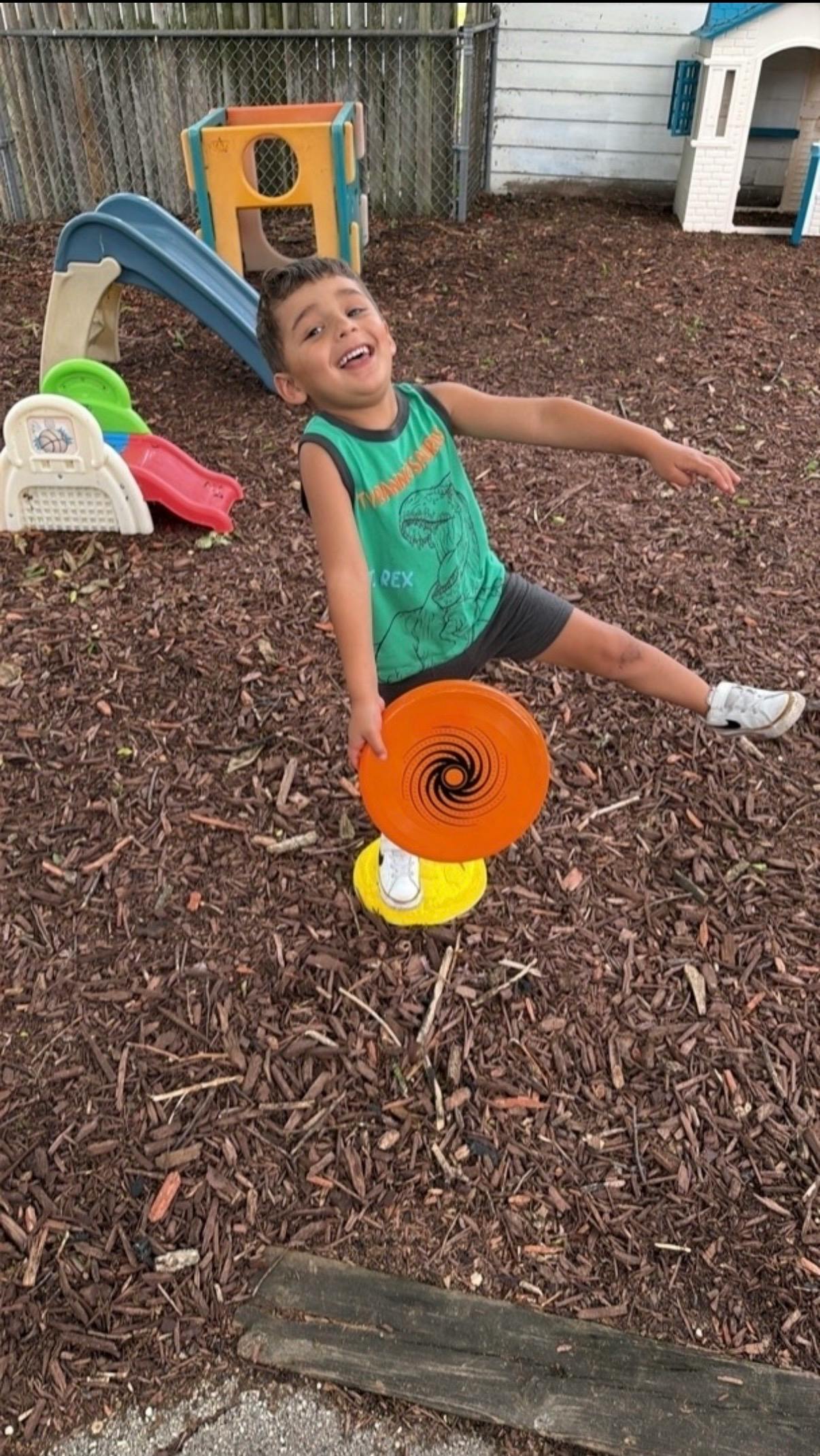 Child balancing on a toy on a playground with a frisbee