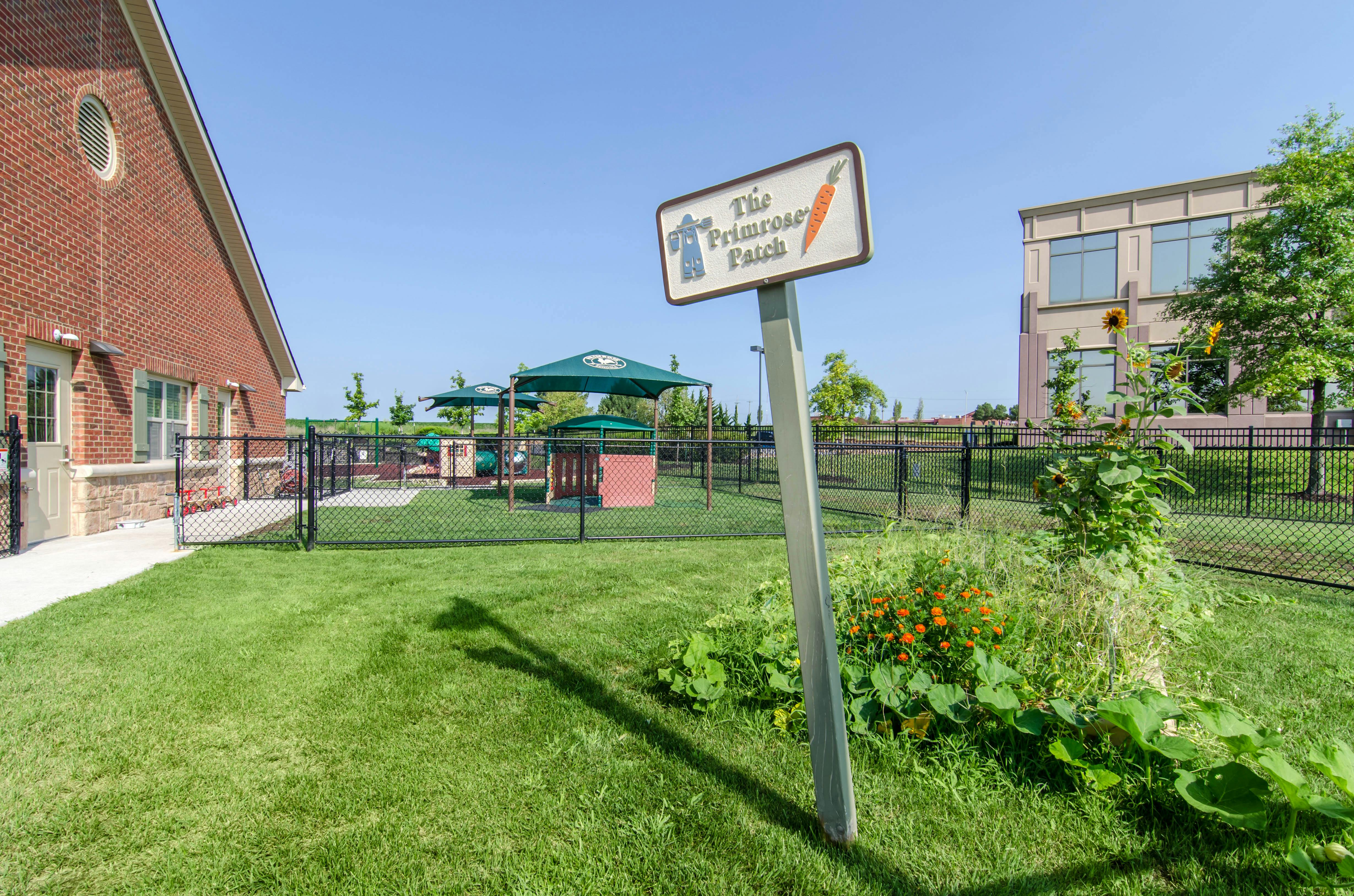 Sign for The Primrose Patch by a playground and building