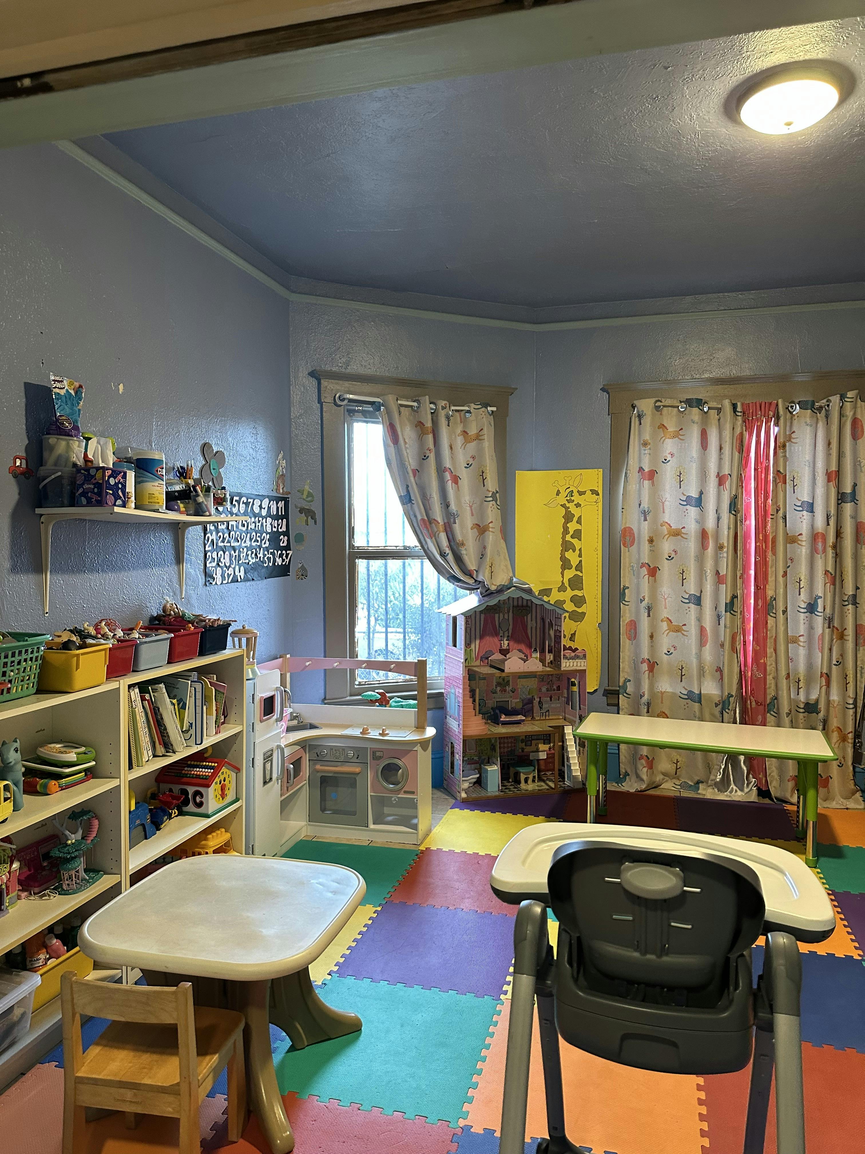 Playroom with children furniture, toy kitchen, dollhouse, and foam floor mats