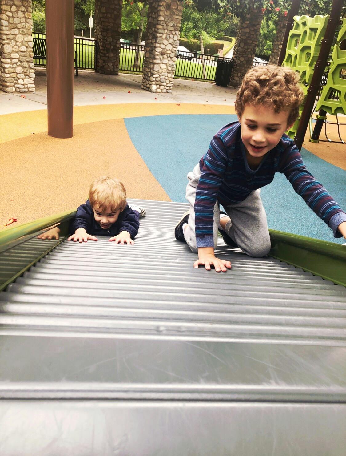 Two children climbing up a slide on a playground