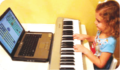 Child playing a keyboard next to a laptop
