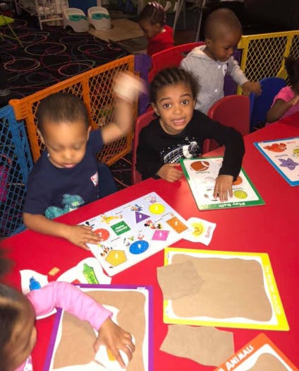 Children at a red table with learning activities