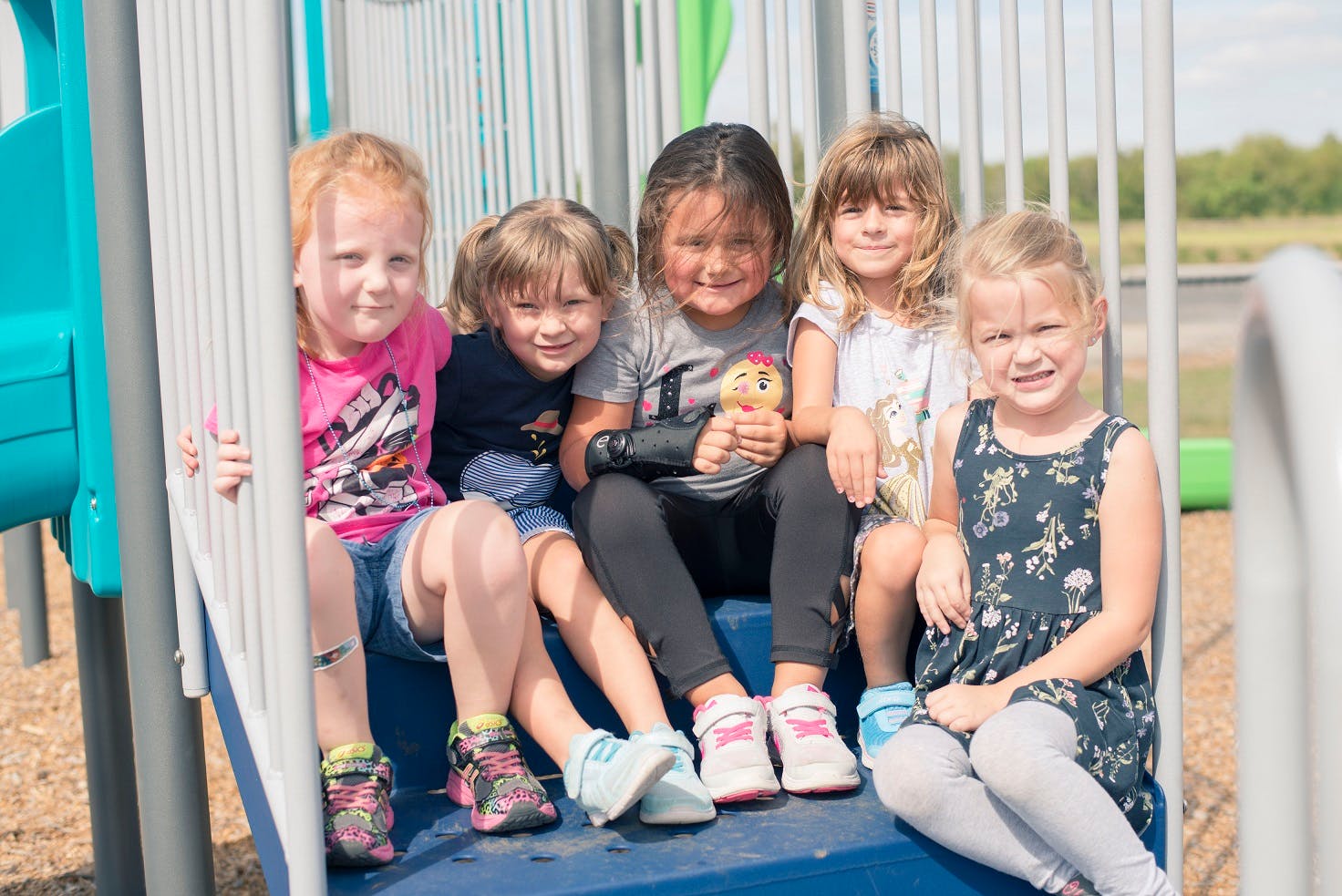 Five children sitting on a playground structure