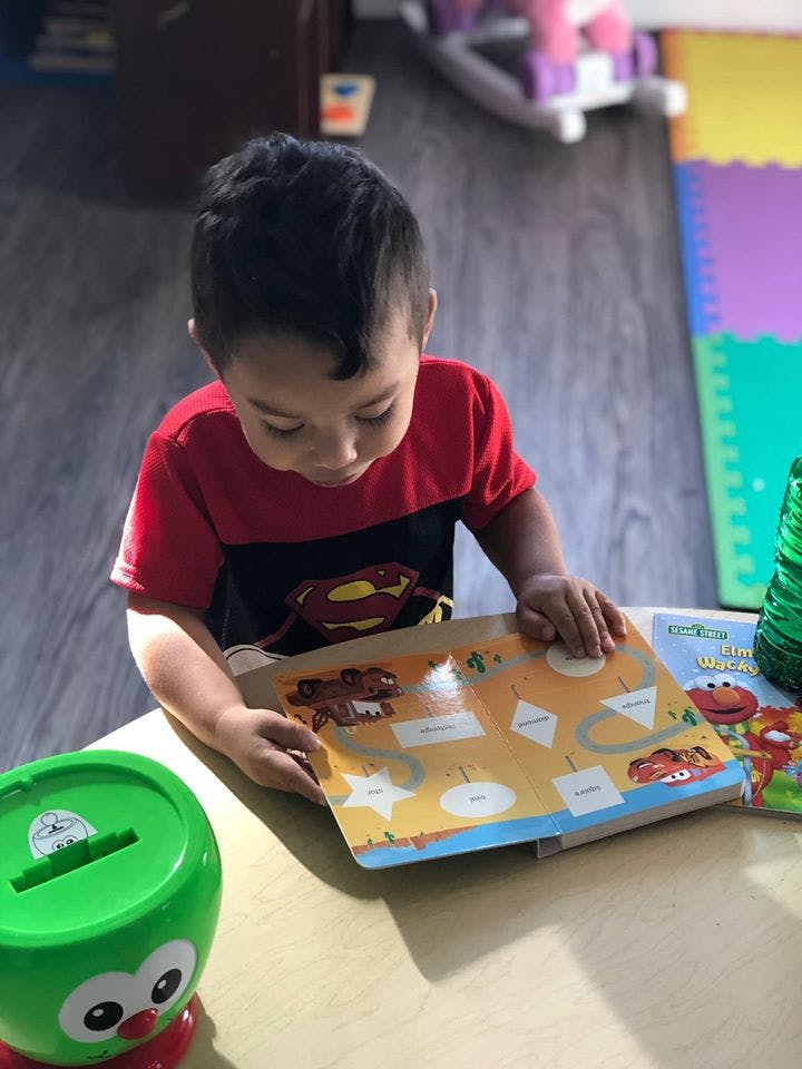 Child looking at a book with shapes and cars