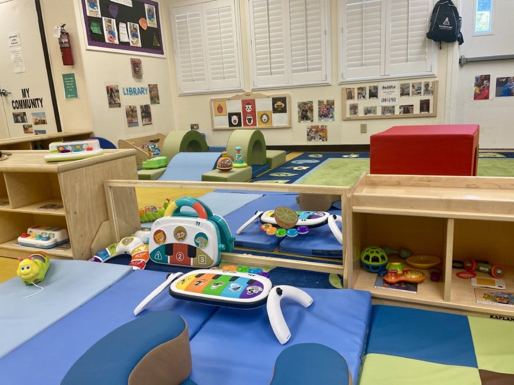 Classroom filled with play mats, low wooden shelves, and infant toys