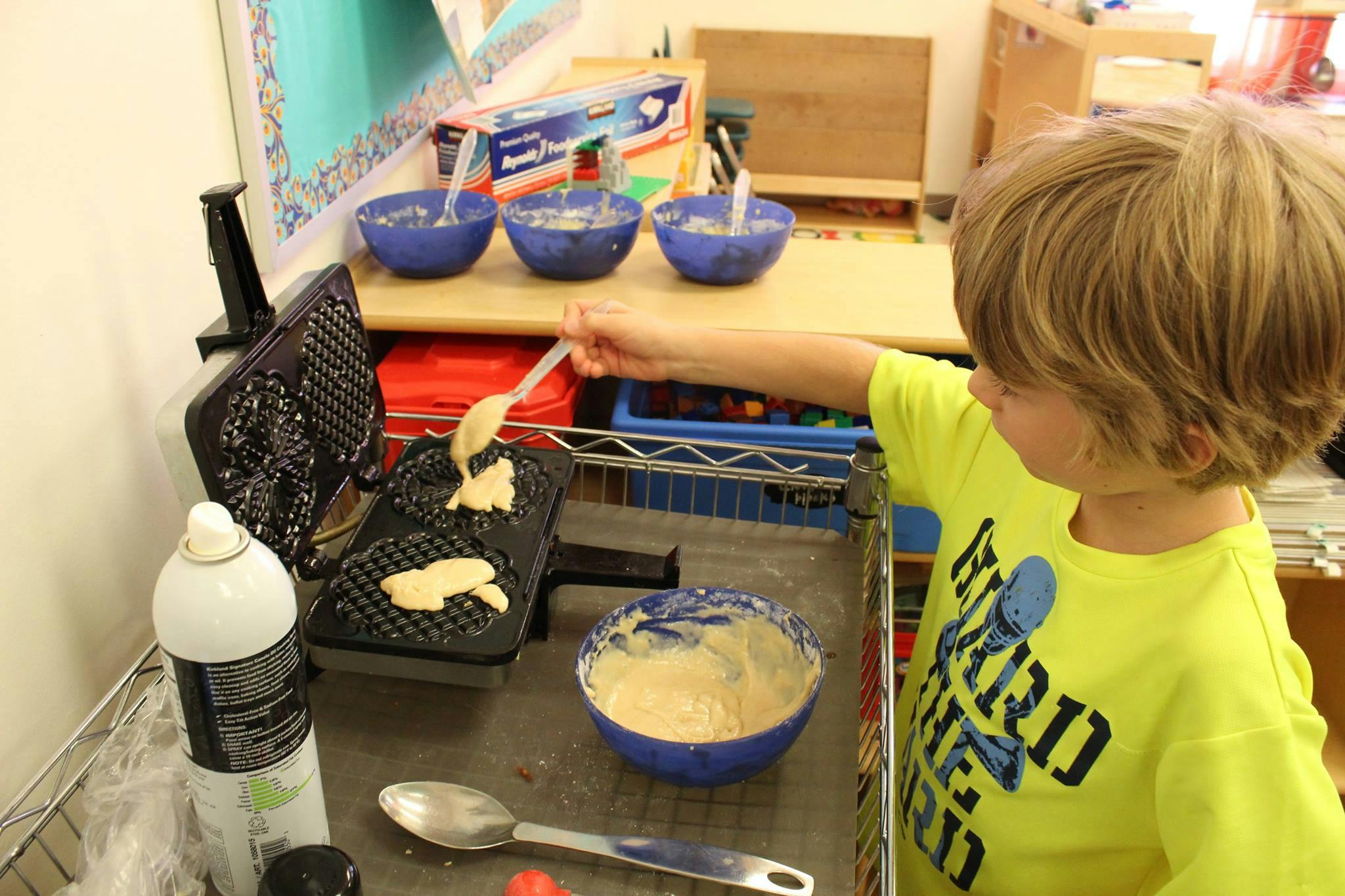 Child putting batter into a waffle maker