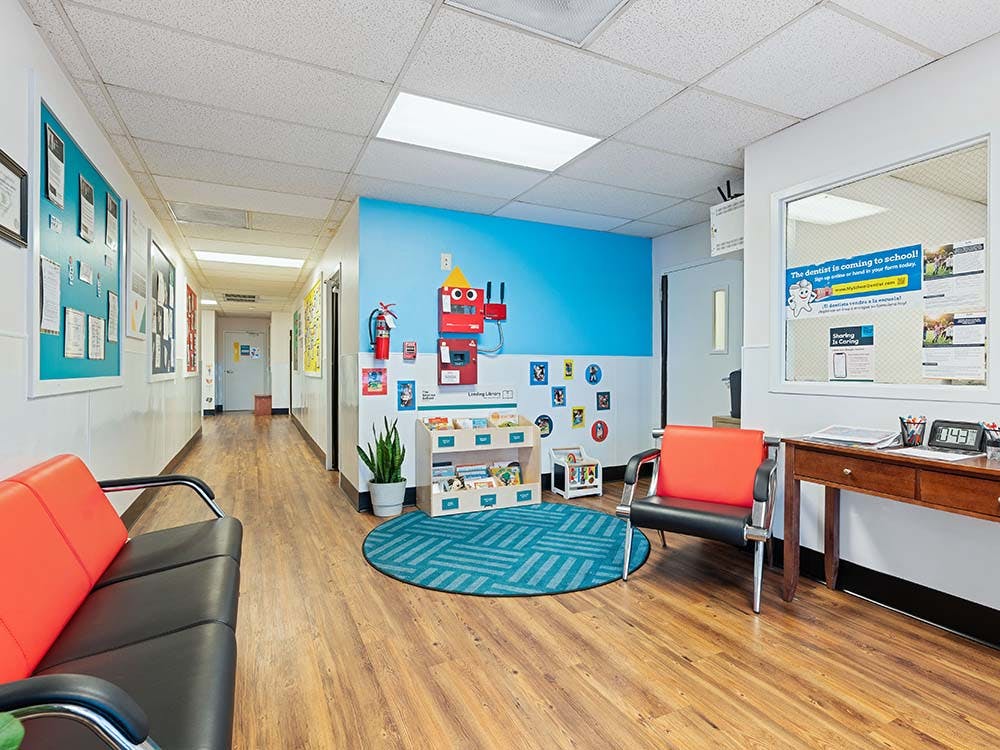 Waiting area with a bright blue wall, a circular blue rug, and seating
