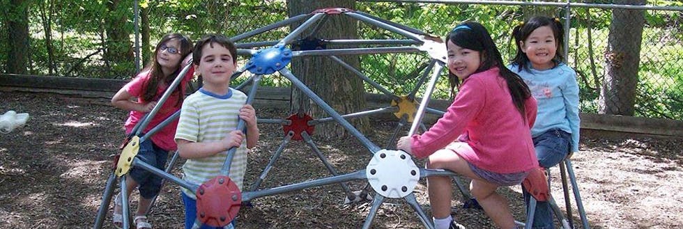 Four children on a playground climbing dome
