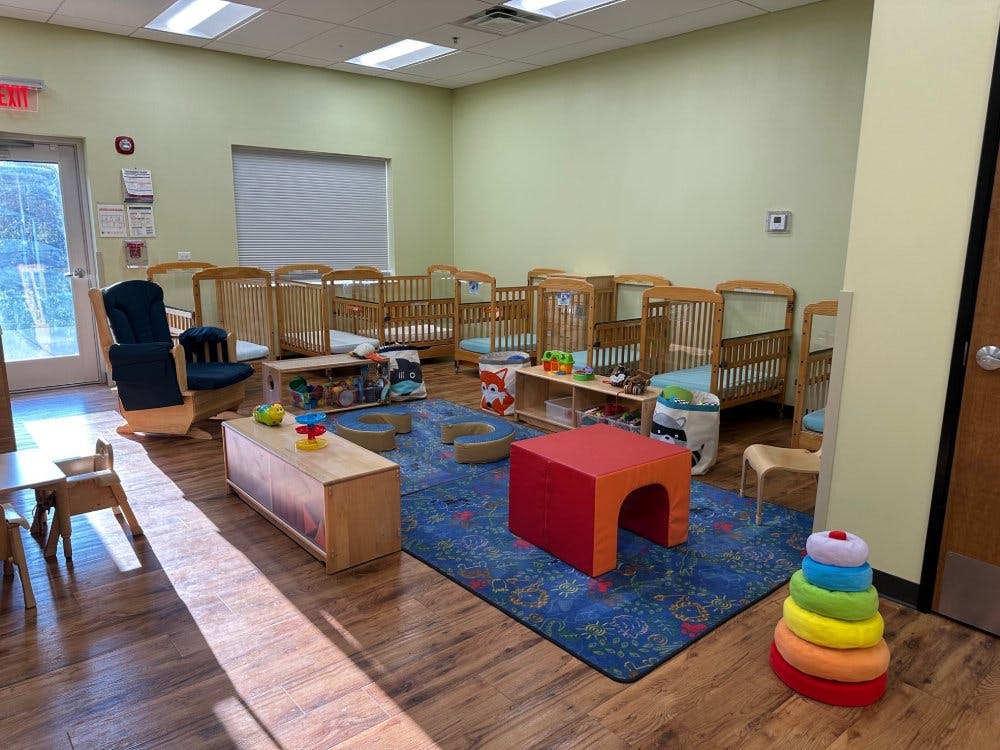 Cribs in a daycare room with a rocking chair and child-sized furniture