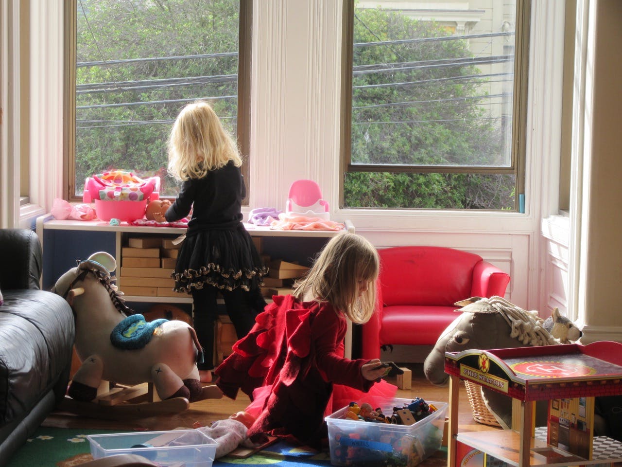 Two children playing with toys in a room with large windows
