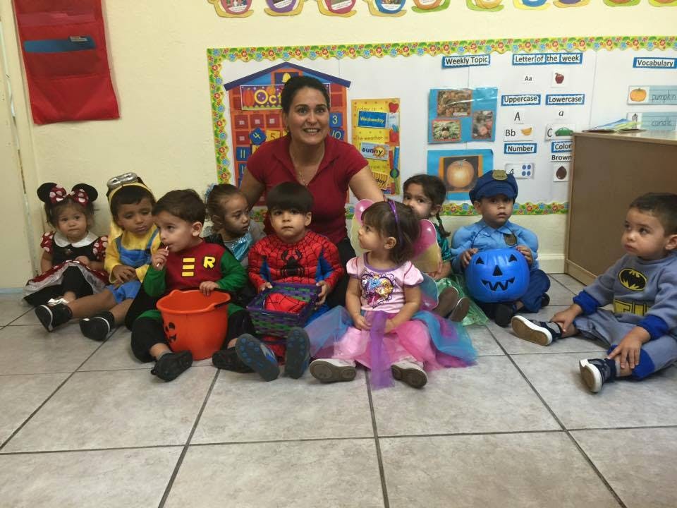 Adult and children in costumes sitting on the floor in a classroom
