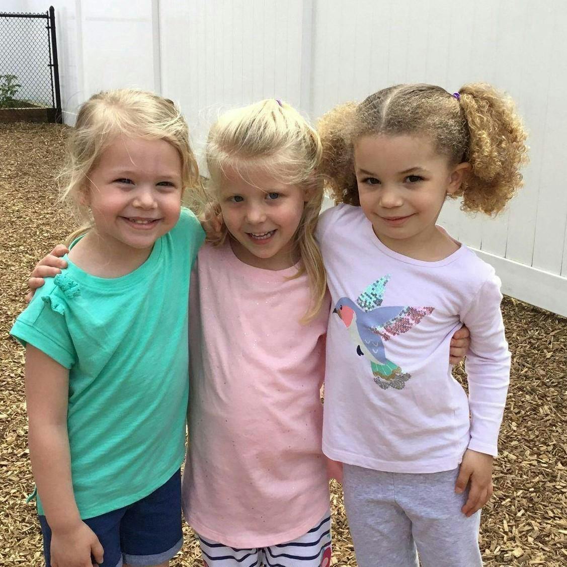 Three children standing together with arms around each other