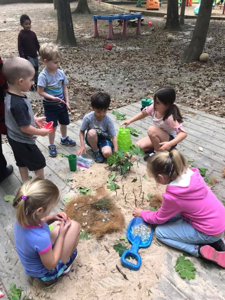 Children playing in a sandbox with toys and natural materials