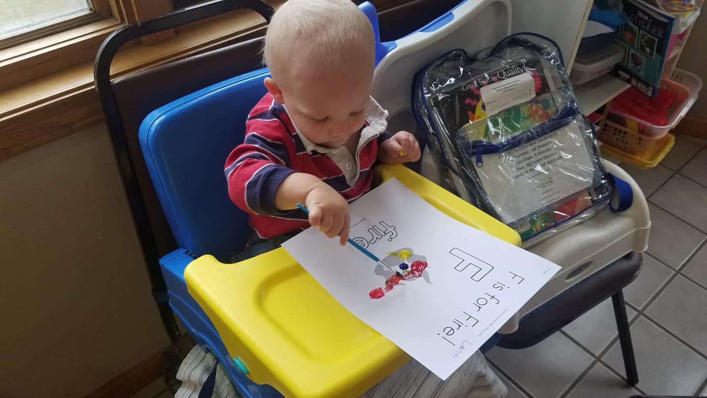 Child in high chair drawing on paper