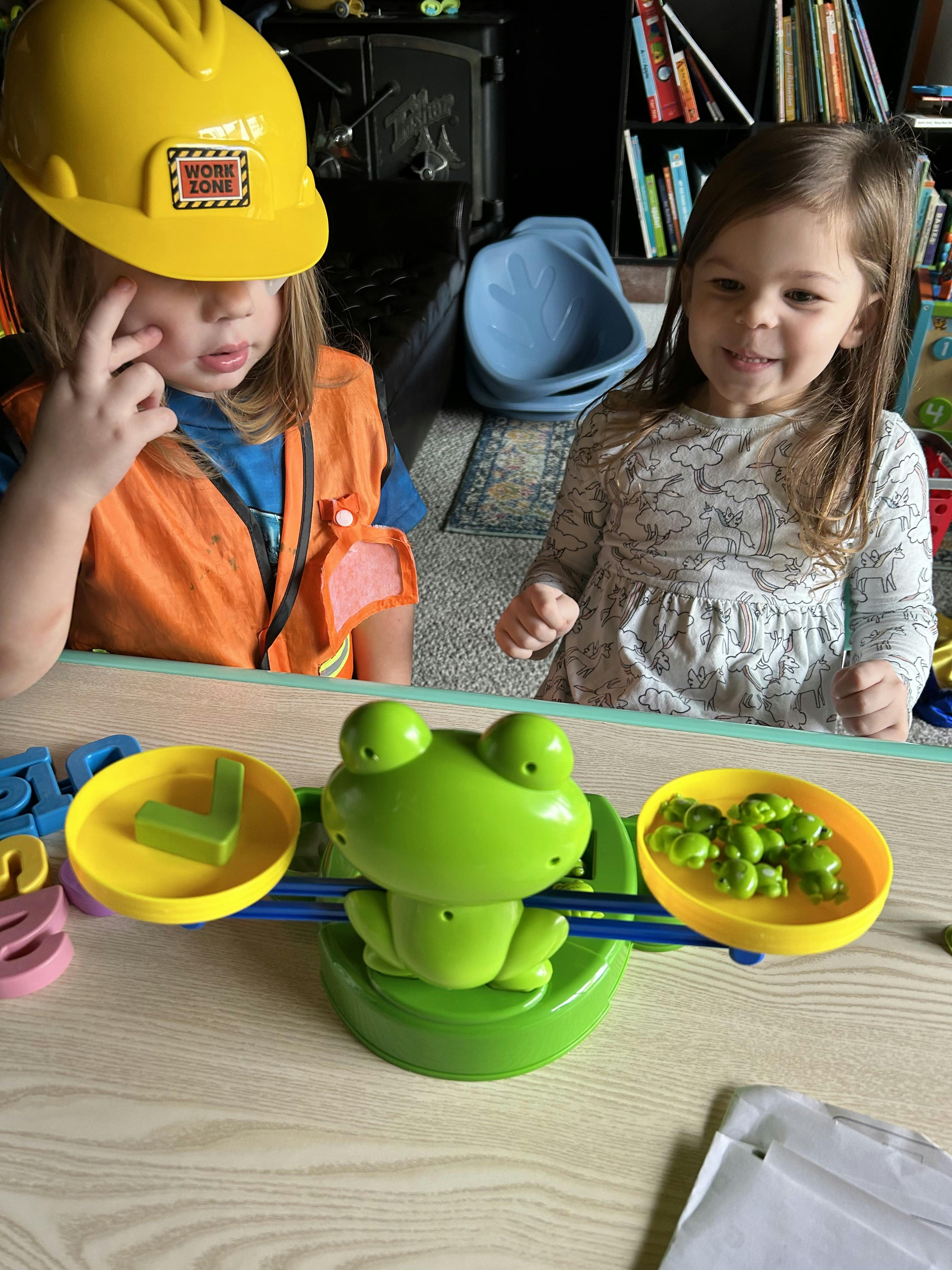 Two children playing with a frog-shaped balance scale