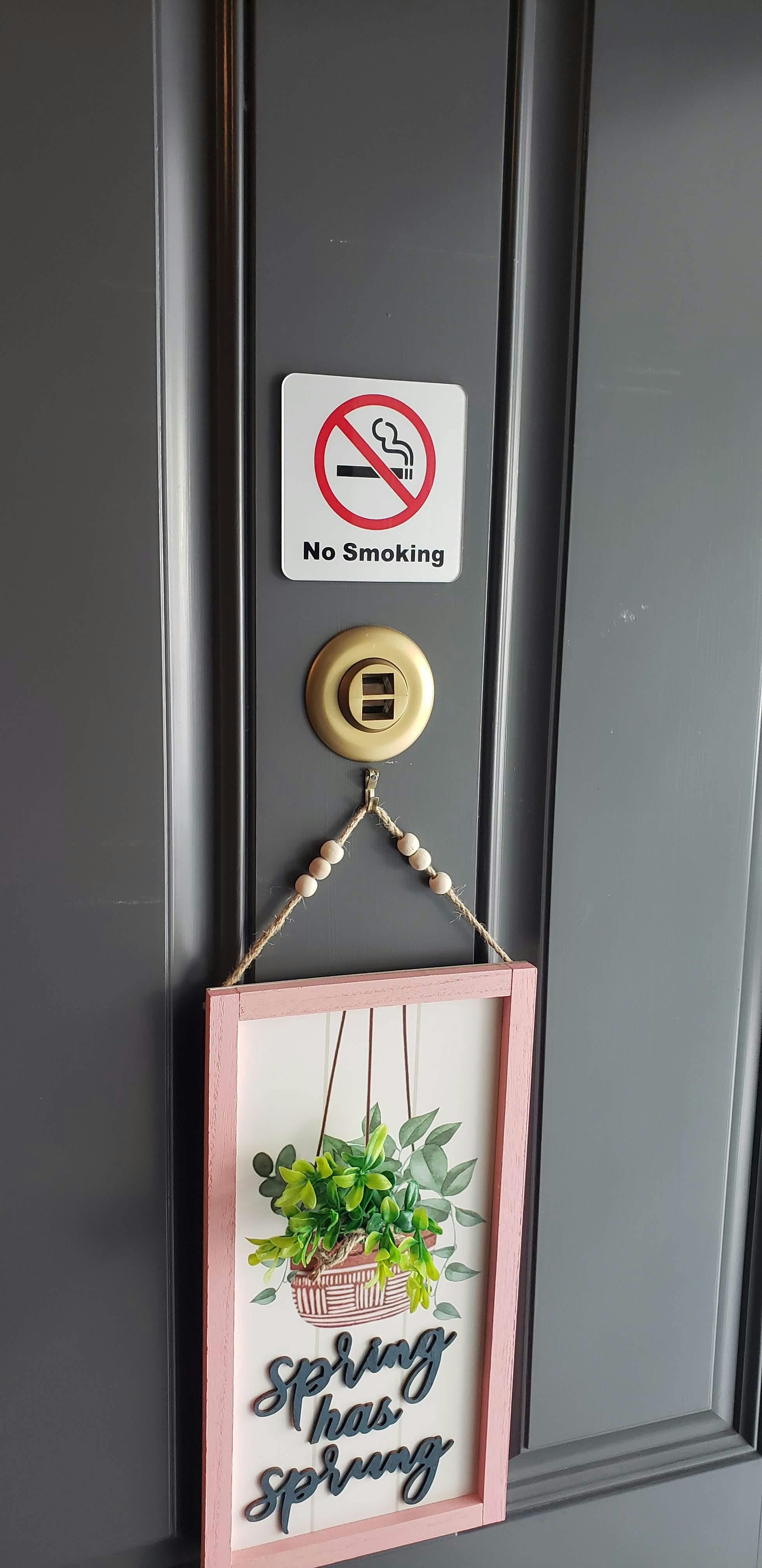 No smoking sign next to a 'Spring has sprung' decorative plaque on a door