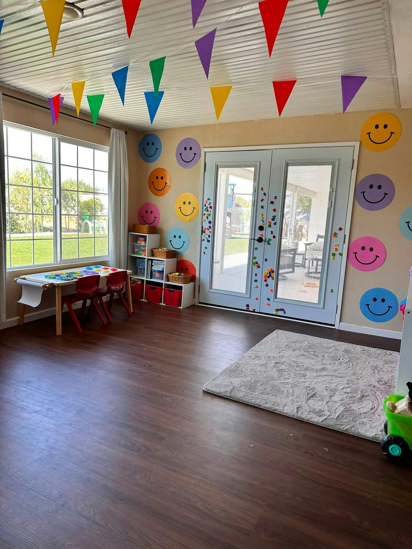 Playroom with smiley face wall decals, bunting flags, and a small table