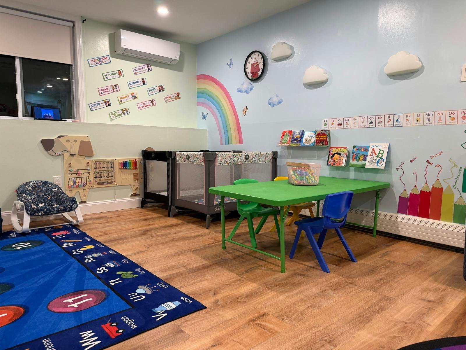 Colorful playroom with small furniture, a baby playpen, and educational wall art