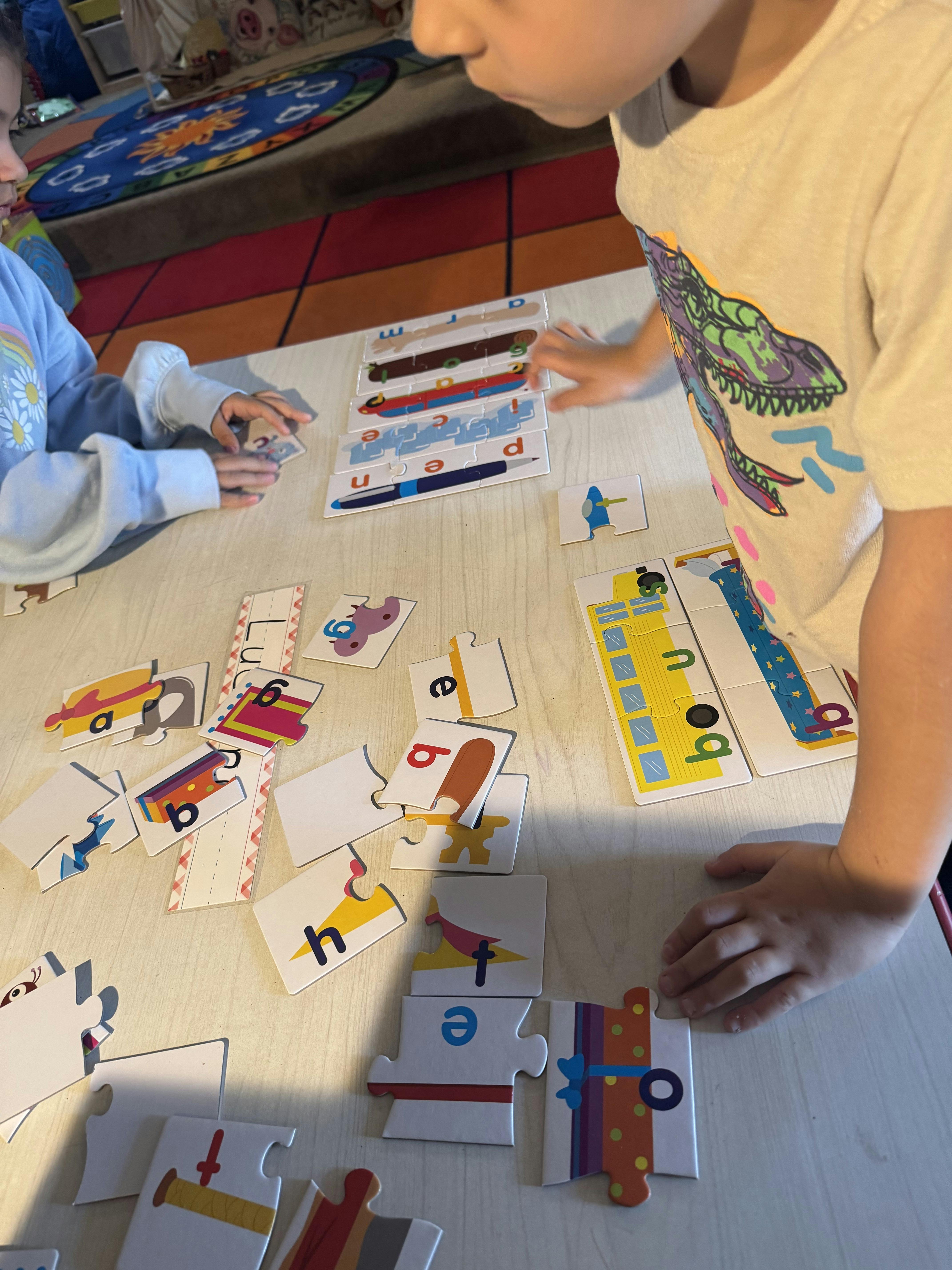Two children playing with letter and word puzzles on a table