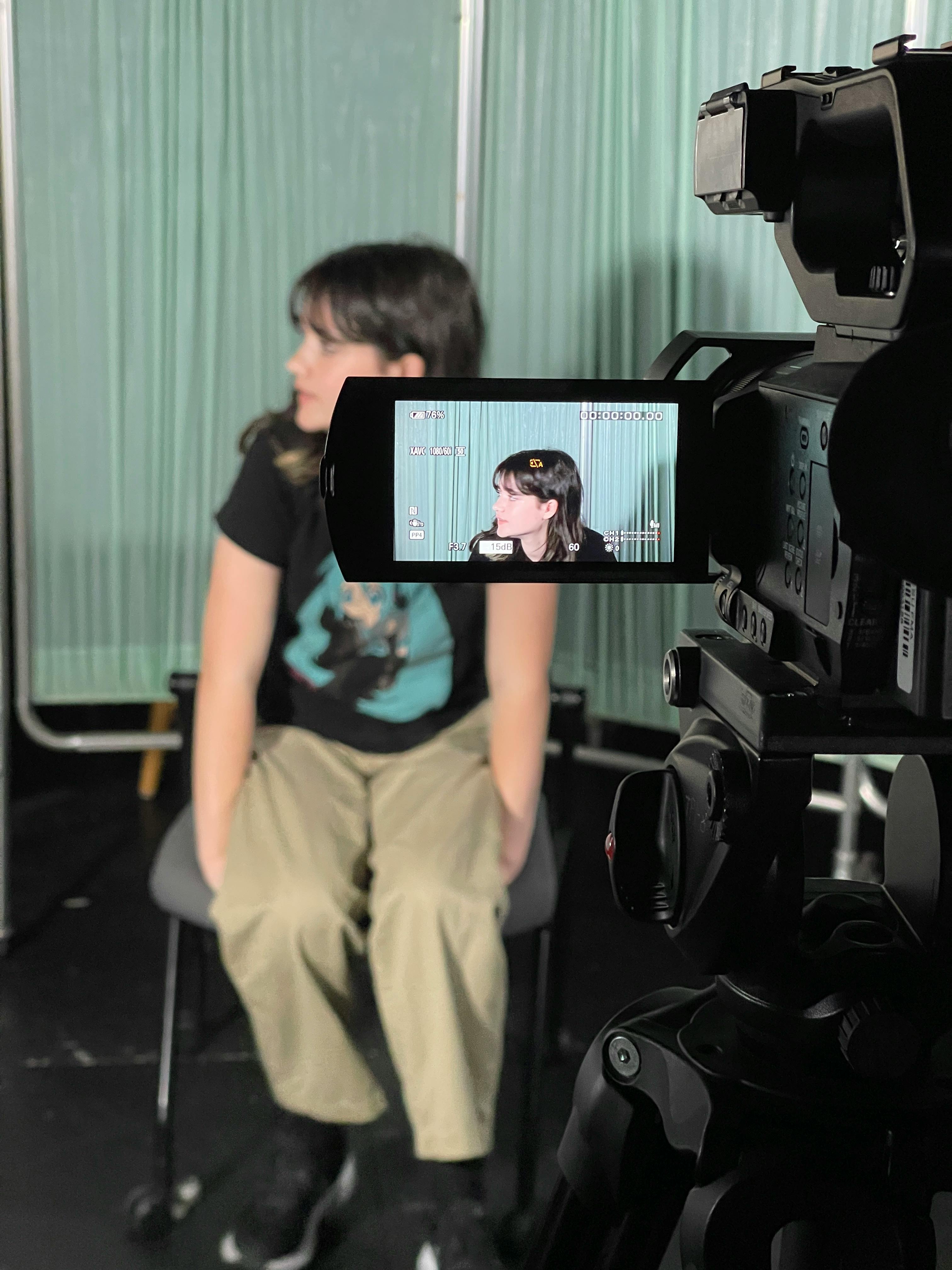 Child sitting in front of a camera, visible on the camera's screen