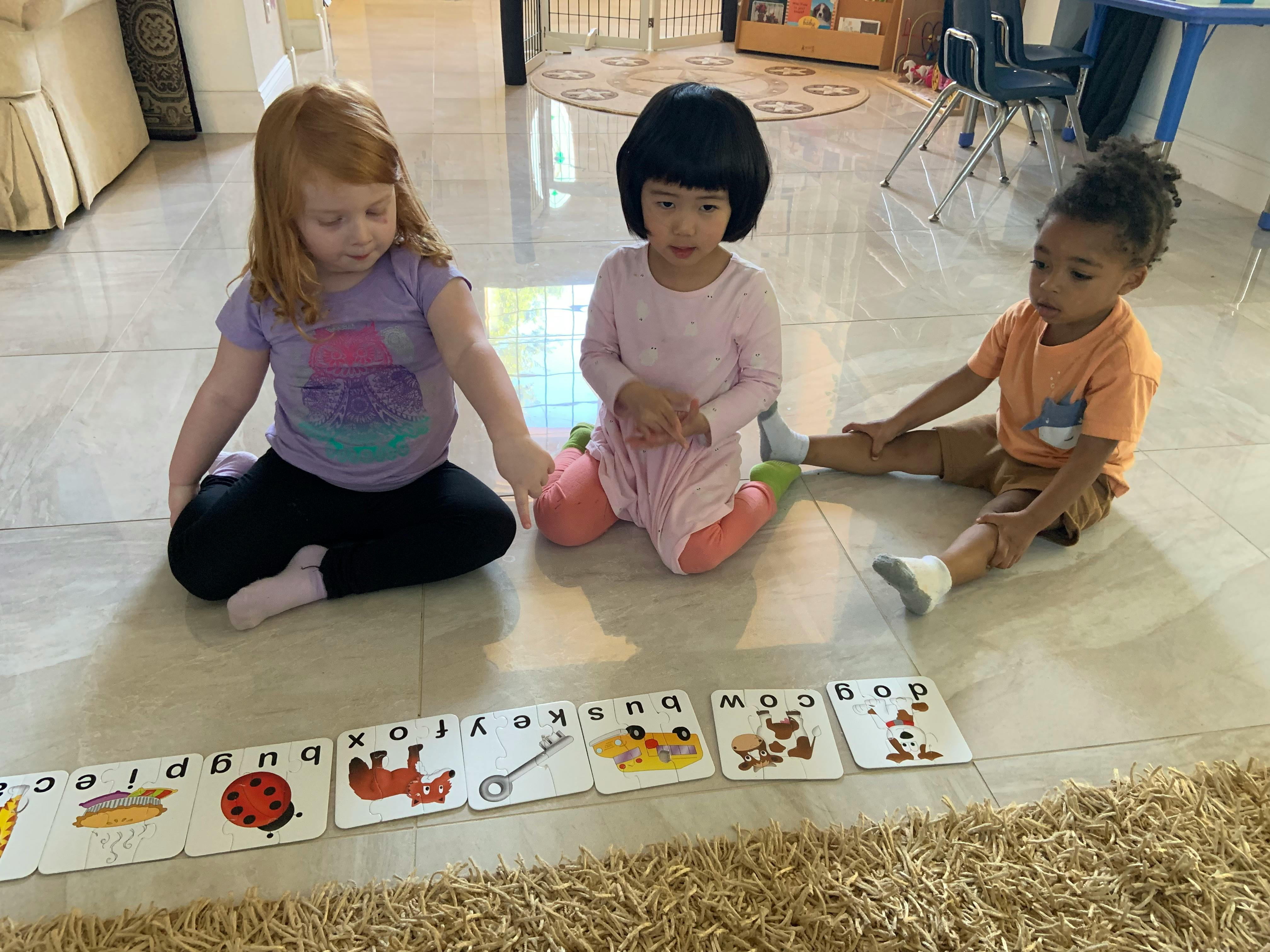 Three children sitting on the floor looking at flashcards